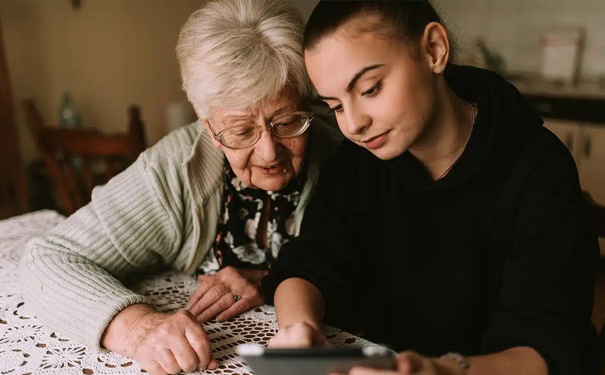 A caregiver teaches an older woman how to use gadgets. | In-Home Senior Care Services